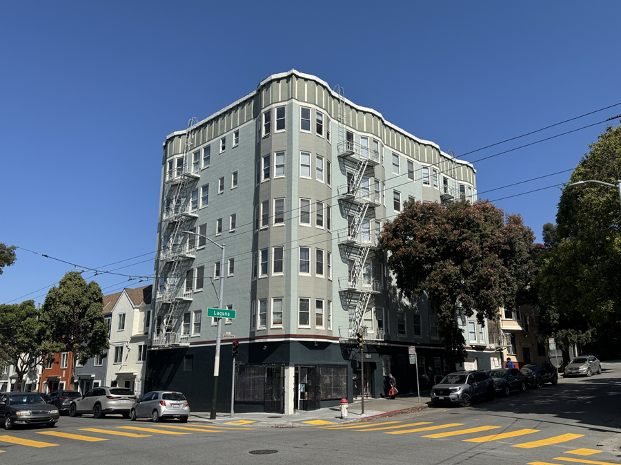 A street view of a tall building with a fire escape on the side.
